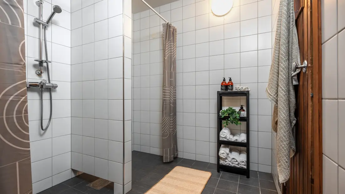 Felles dusj som hører til sauna, dusjforheng og håndklær.
