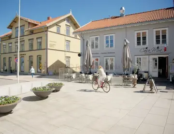 Bilde av en dame som sykler forbi inngangen til en restaurant