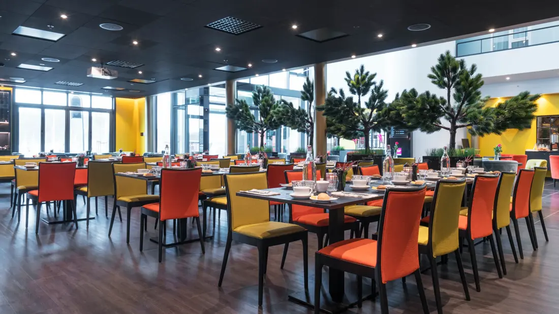 Frokostsal med gule og orange stoler og planter på Thon Hotel Nodlys i Bodø sentrum