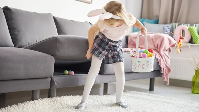 Liten jente med kaninhårbøyle som leter etter påskeegg