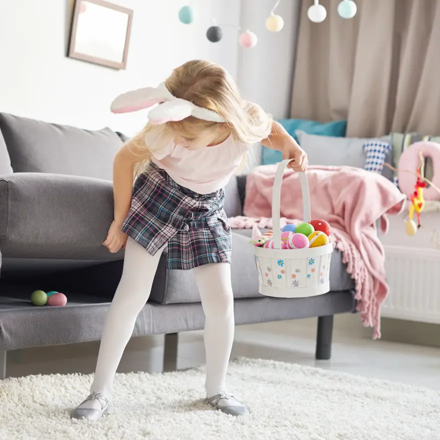 Liten jente med kaninhårbøyle som leter etter påskeegg