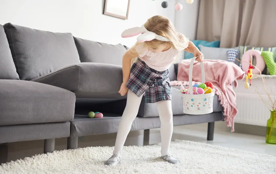 Liten jente med kaninhårbøyle som leter etter påskeegg