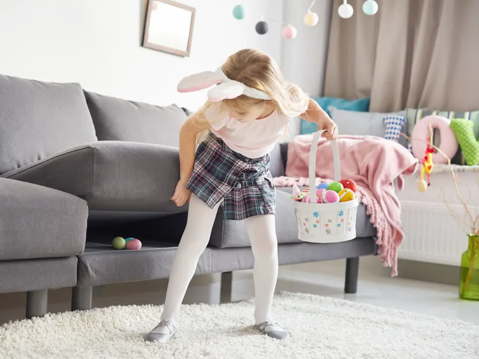 Liten jente med kaninhårbøyle som leter etter påskeegg