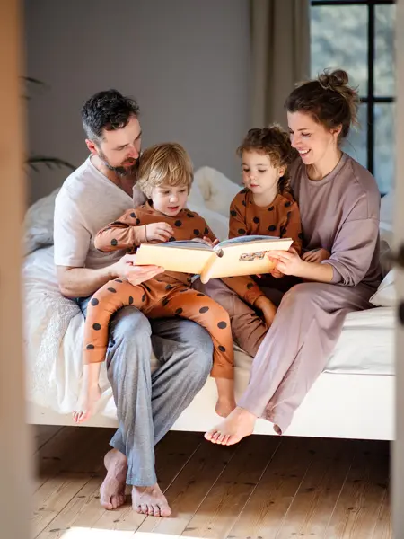 Mother and father with son and daughter spending time together at bedtime.
