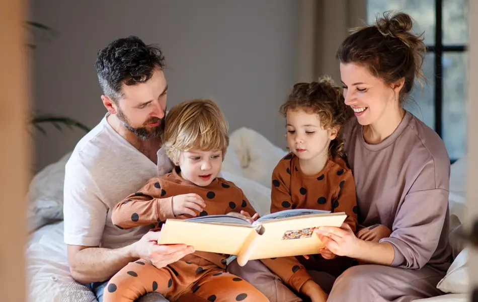 Mother and father with son and daughter spending time together at bedtime.