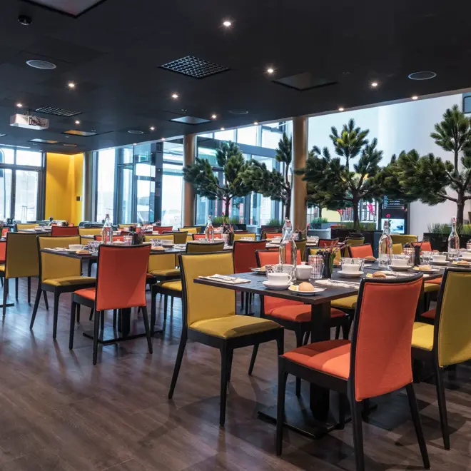 Frokostsal med gule og orange stoler og planter på Thon Hotel Nodlys i Bodø sentrum