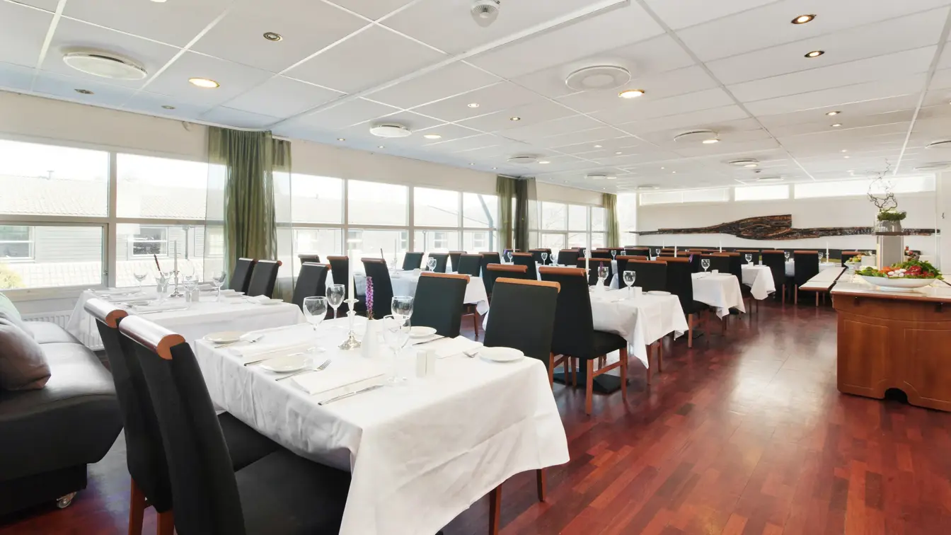 Restaurant med lange bord med hvite duker og sorte stoler i restauranten til Thon Hotel Sandnes