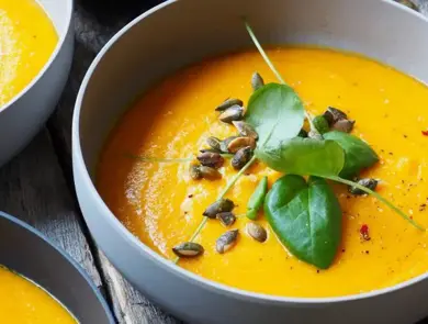 Nærbilde av skåler med gresskarsuppe pyntet med basilikum