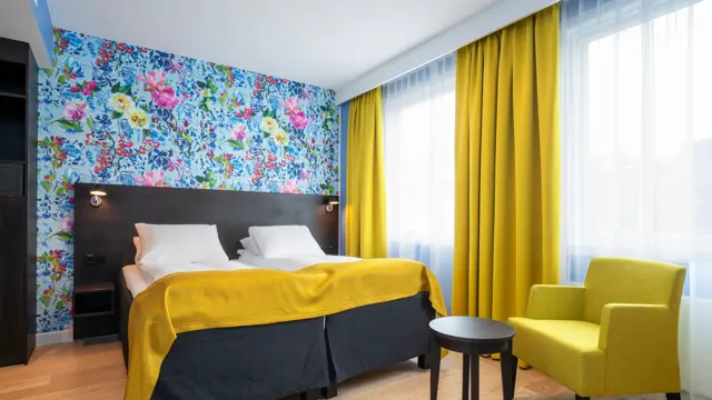 Separate senger, blomstrete tapet og gule gardiner i twin rom på Thon Hotel Moldefjord