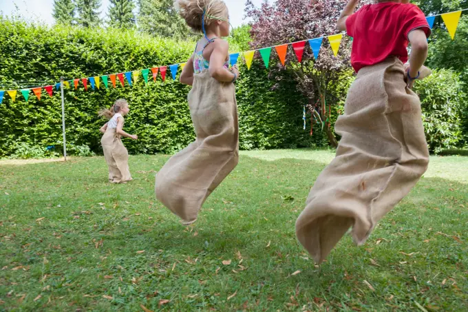 Children having a sack race in garden on a birthday party