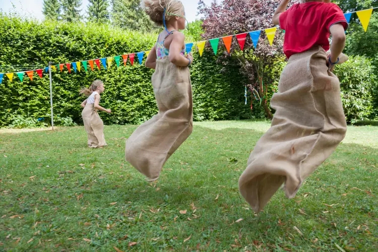 Children having a sack race in garden on a birthday party