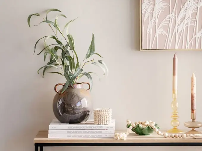 Vase med grønn plante, lysestaker og et bilde