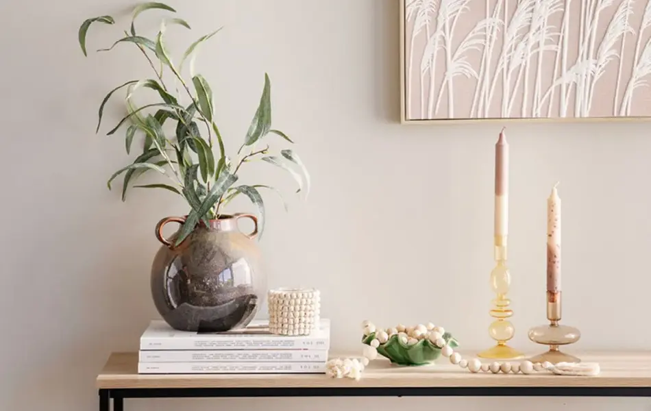 Vase med grønn plante, lysestaker og et bilde