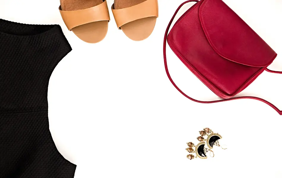 Flat lay of elegant feminine clothing and accessories.  Little black dress, nude sandals, marsala bag and earrings. Fashion blog. Copy space for text