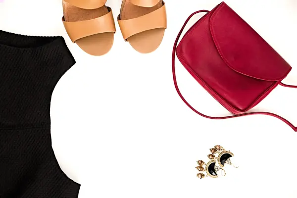 Flat lay of elegant feminine clothing and accessories.  Little black dress, nude sandals, marsala bag and earrings. Fashion blog. Copy space for text
