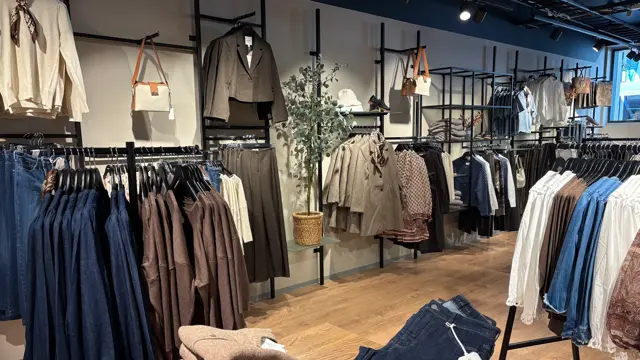 Vegg og bord med klær i fargene brunt, beige og mørk ola