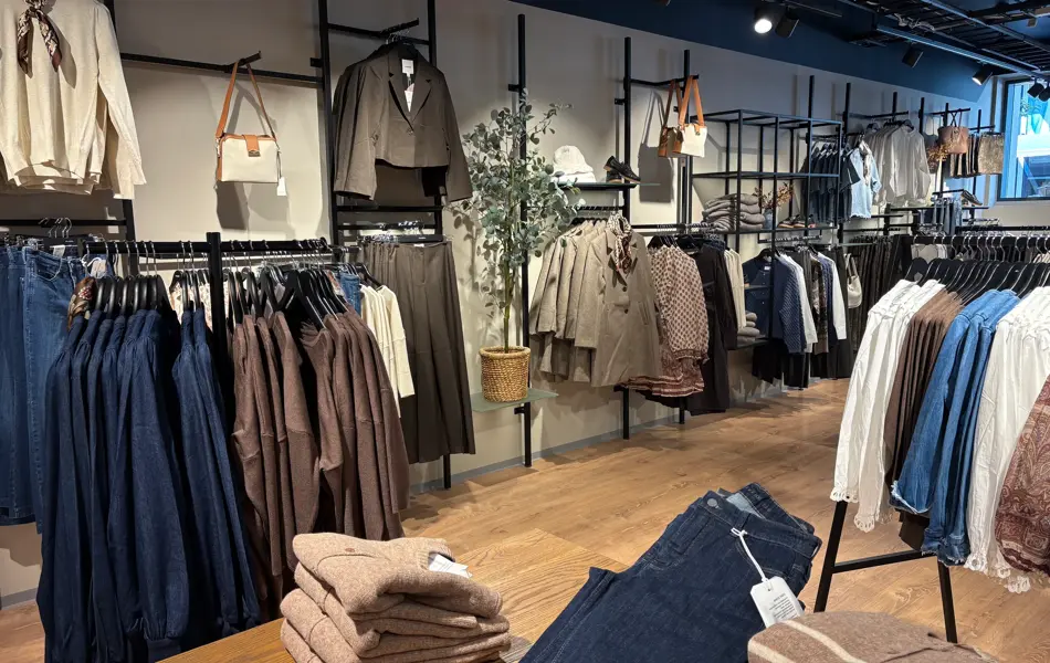 Vegg og bord med klær i fargene brunt, beige og mørk ola