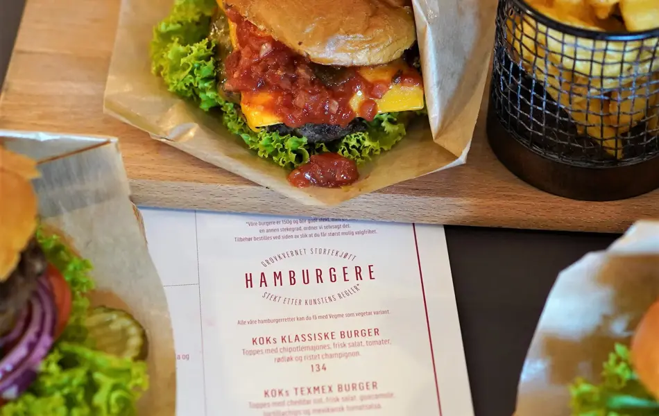 Burgere og fries på trefjøler med meny i midten