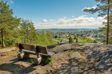 Bilde av en benk på et fjell, med utsikt over Strømmen
