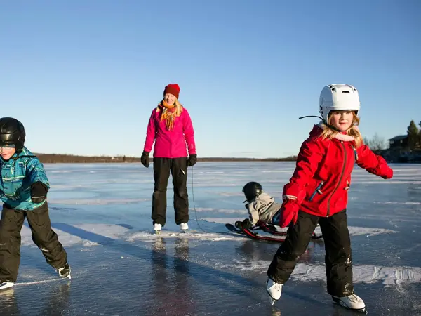 Tre barn og en voksen på skøyter utendørs
