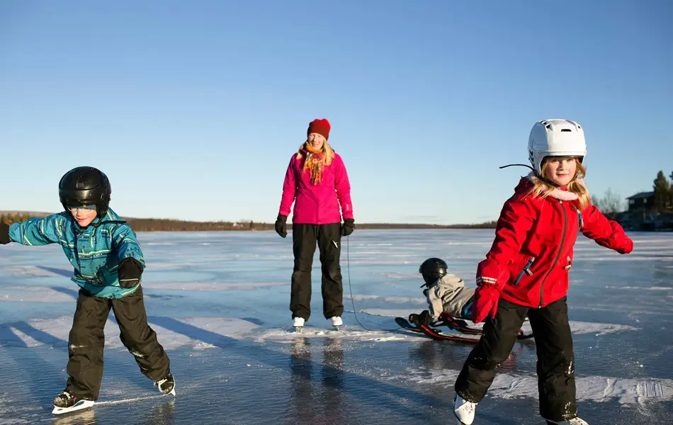 Tre barn og en voksen på skøyter utendørs