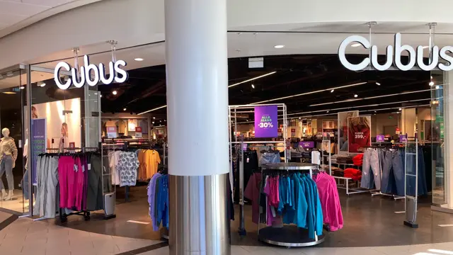 innendørs butikk med skilt og klær bak en søyle