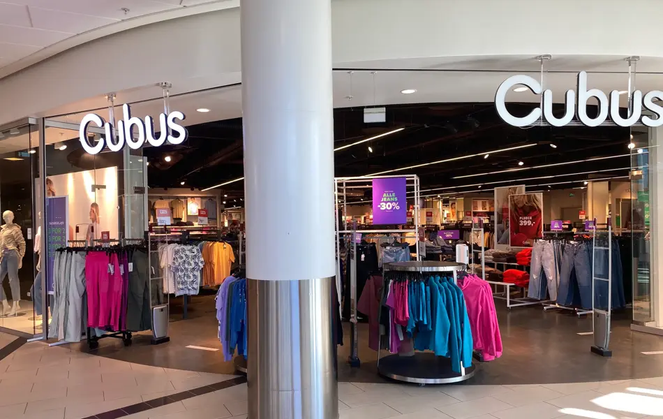 innendørs butikk med skilt og klær bak en søyle