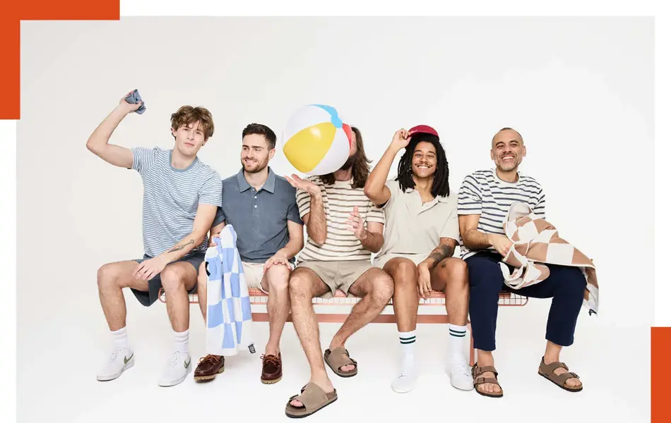 En gjeng menn sitter på en benk med håndkle, badeball, shorts og t-skjorte og skjorter.