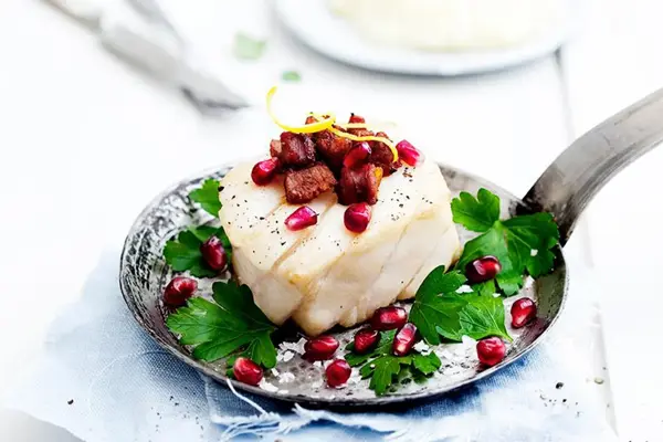 Tilbered skrei med bacon dekorert med granateple og urter
