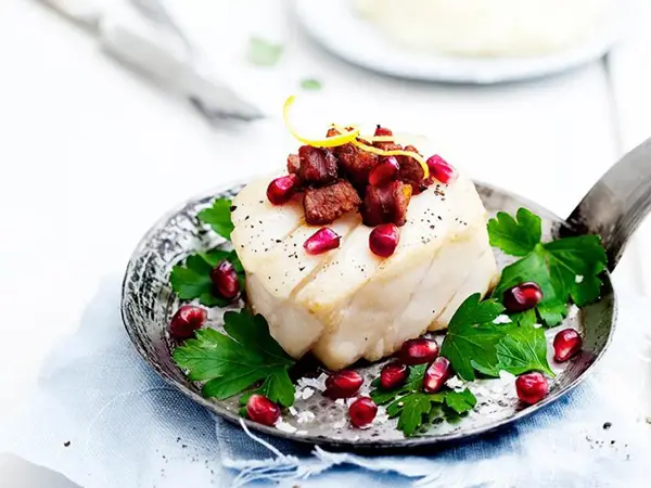Tilbered skrei med bacon dekorert med granateple og urter