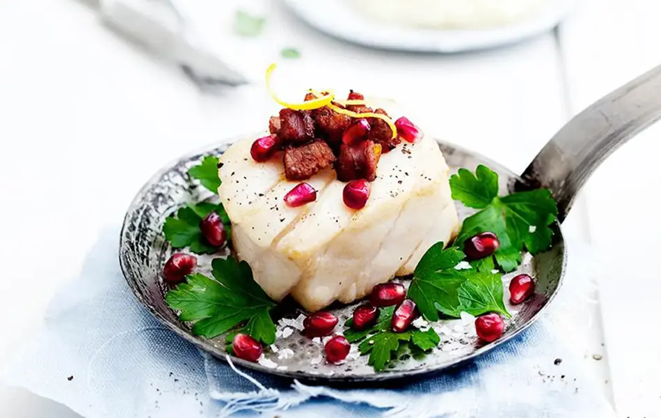 Tilbered skrei med bacon dekorert med granateple og urter