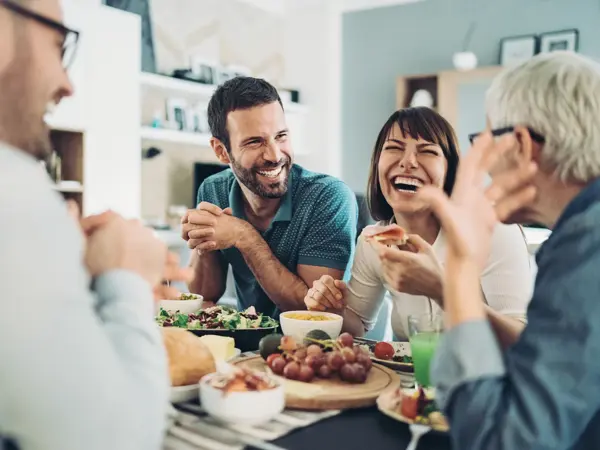 Group of friends gathered around the table with food and drinks, having good time together
