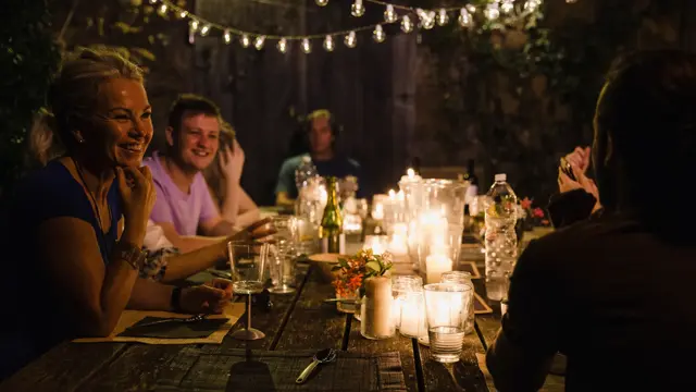 Gruppe ved bordet om kvelden opplyst av lykter og stearinlys