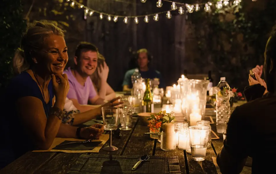 Gruppe ved bordet om kvelden opplyst av lykter og stearinlys