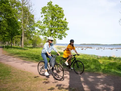 To Kvinner på hver sin sykkel på kyststien mellom Horten og Åsgårdstrand. I bakgrunnen ses Oslofjorden og Bastøy.