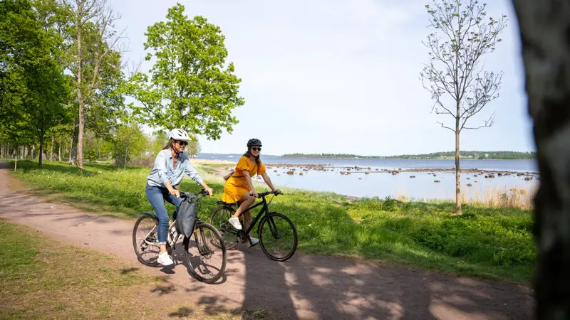 To Kvinner på hver sin sykkel på kyststien mellom Horten og Åsgårdstrand. I bakgrunnen ses Oslofjorden og Bastøy.