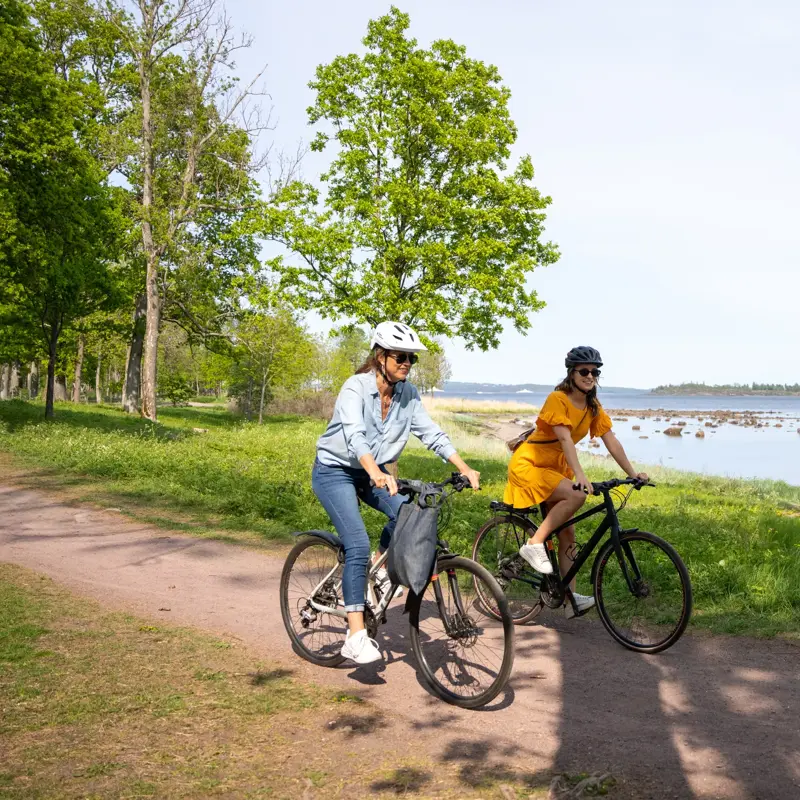 To Kvinner på hver sin sykkel på kyststien mellom Horten og Åsgårdstrand. I bakgrunnen ses Oslofjorden og Bastøy.