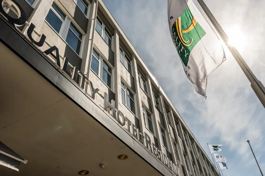 Fasaden til Quality Hotel Residence med flagg og blå himmel