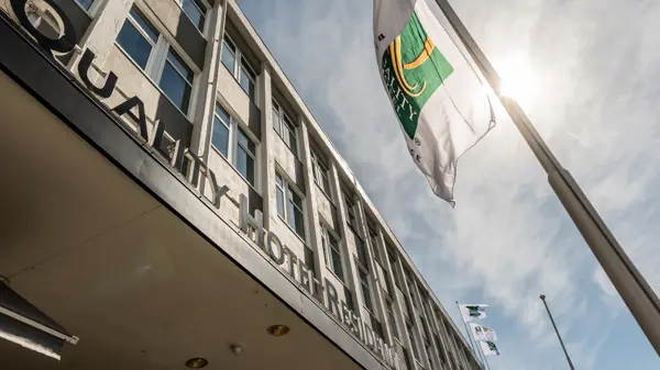 Fasaden til Quality Hotel Residence med flagg og blå himmel