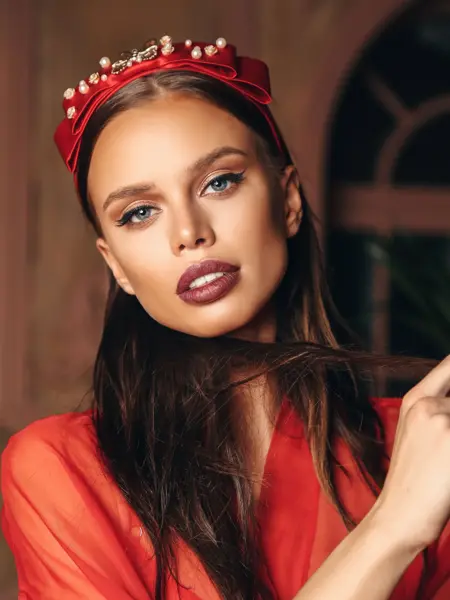 Modell som poserer med rød hårbøyle med perler på