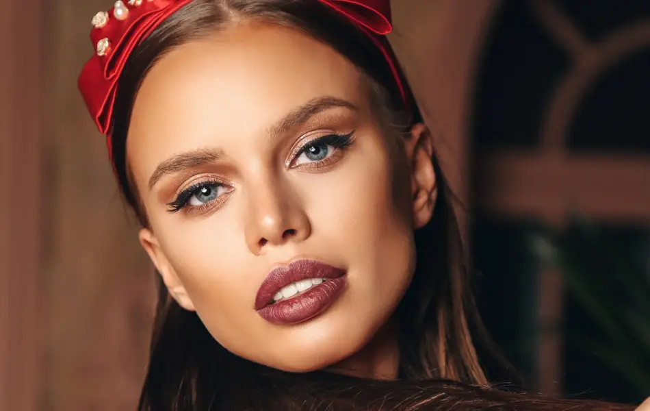 Modell som poserer med rød hårbøyle med perler på