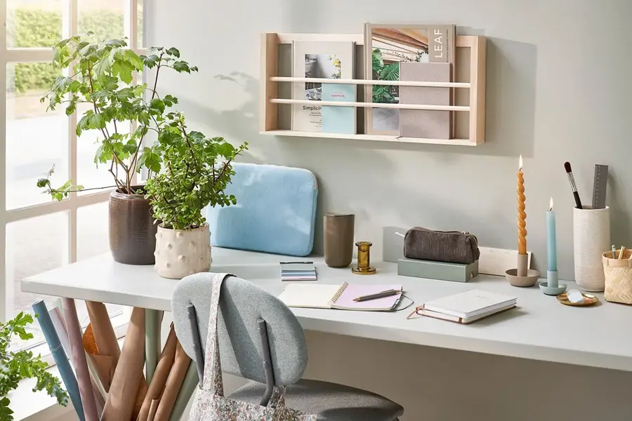 Skrivebord med tegne og skrive saker, lysestaker, potter med planter og mer