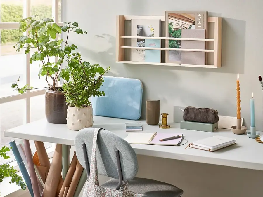 Skrivebord med tegne og skrive saker, lysestaker, potter med planter og mer