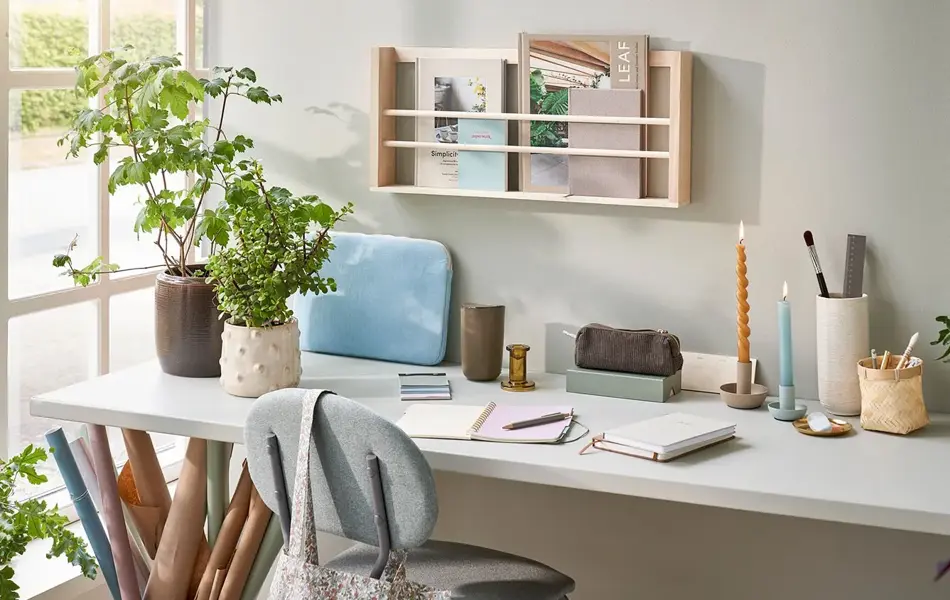 Skrivebord med tegne og skrive saker, lysestaker, potter med planter og mer