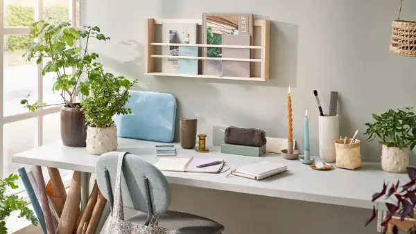 Skrivebord med tegne og skrive saker, lysestaker, potter med planter og mer