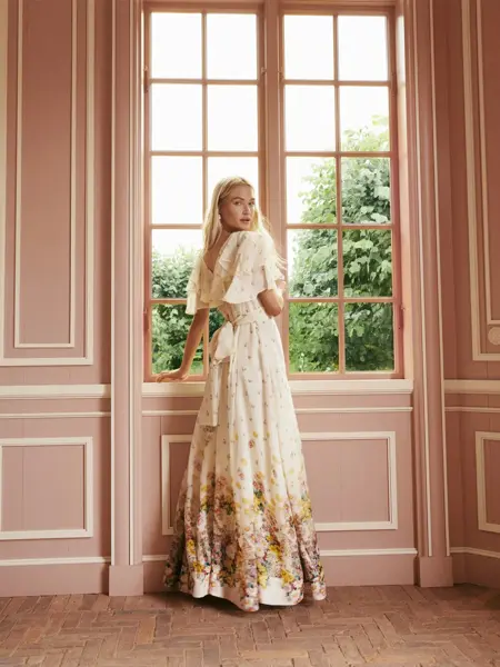 Dame i kjole som står ved et vindu