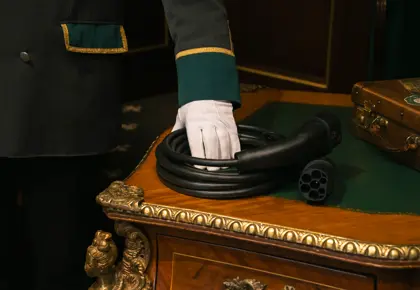 Ladekabel ligger på et bord som blir holdt av en ansatt med uniform og hvit hanske.