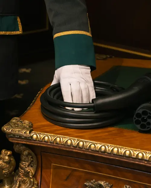 Ladekabel ligger på et bord som blir holdt av en ansatt med uniform og hvit hanske.