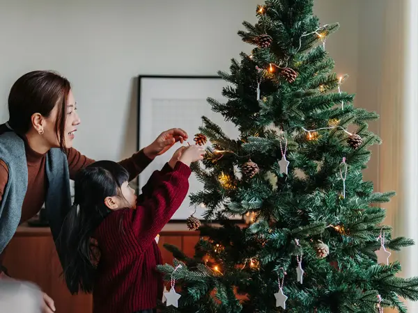 mor og datter som dekorer juletre sammen