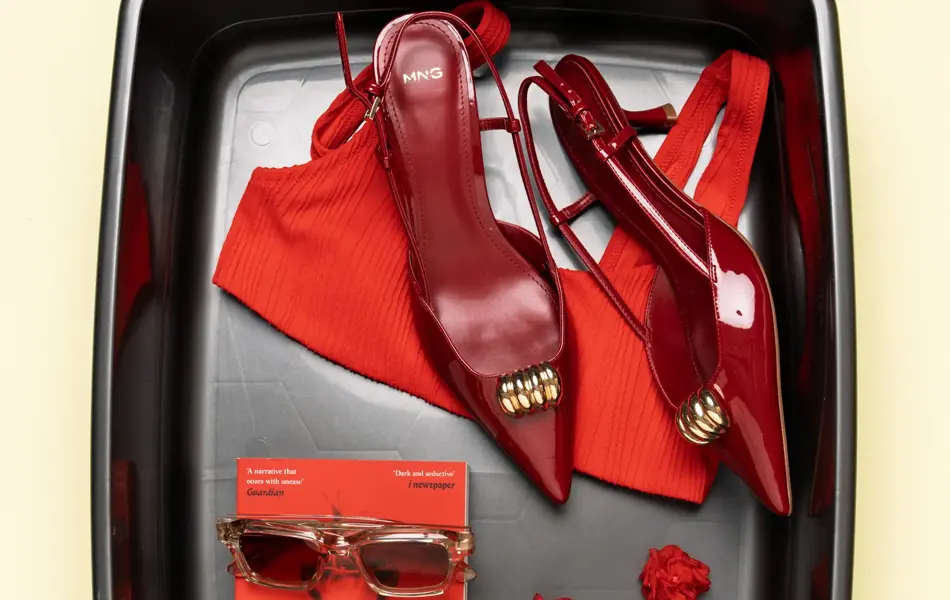 Bokd med rød bikinioverdel, rød pumps, rød bok, solbriller og rød øredobber.